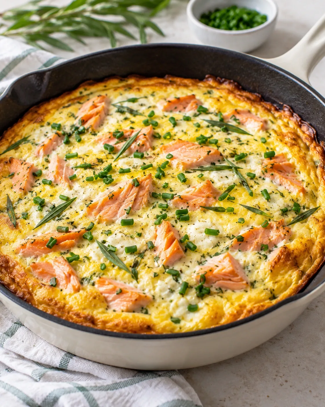 Baked salmon omelet with tarragon and chives in a skillet.