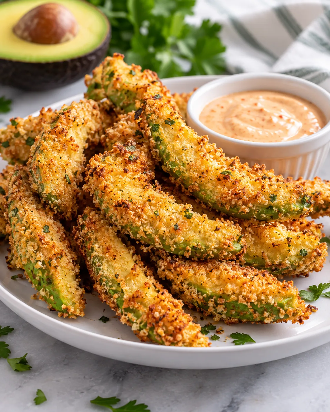 Crispy baked avocado fries arranged on a white plate.