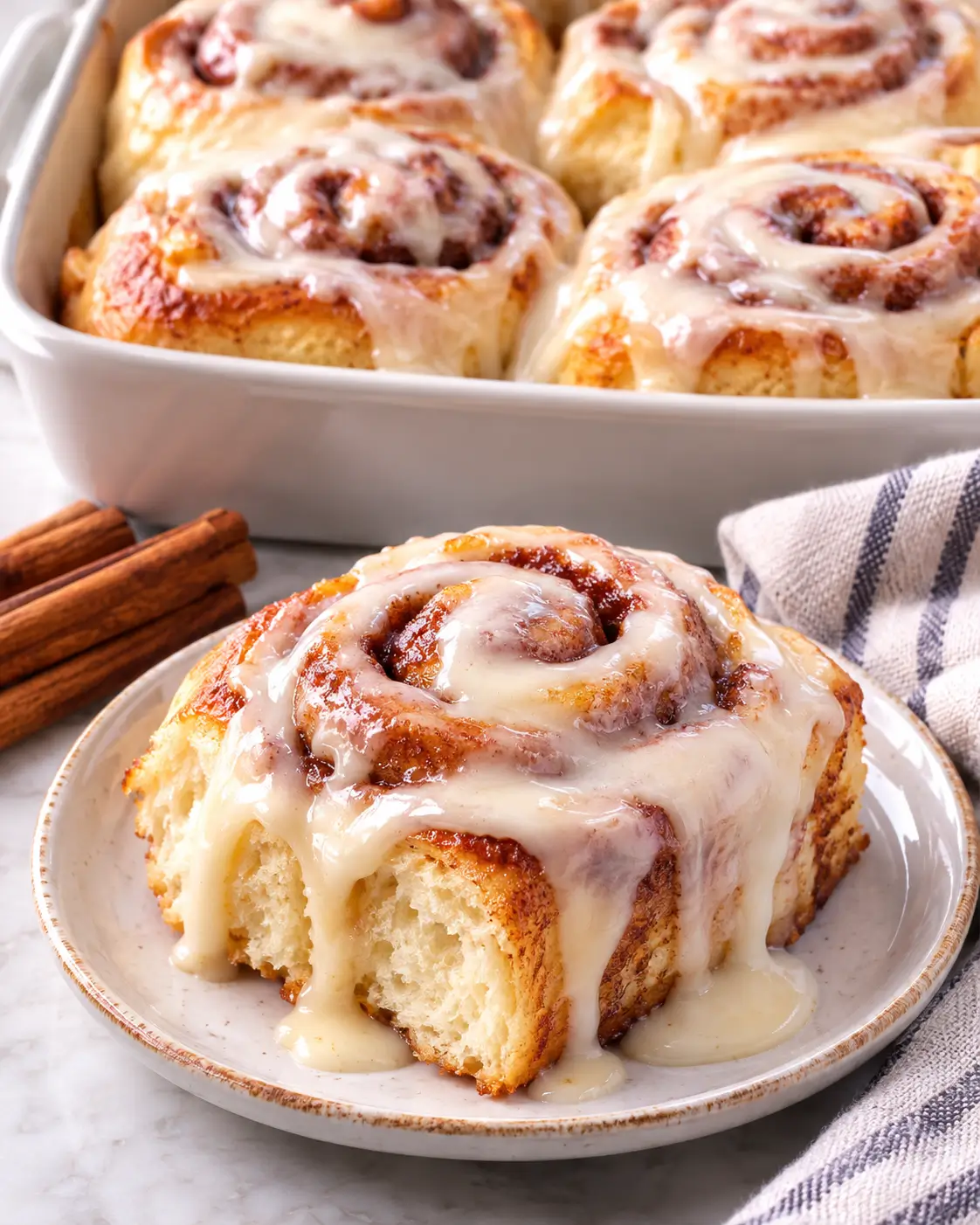 Homemade cinnamon rolls with vanilla glaze in a baking dish.